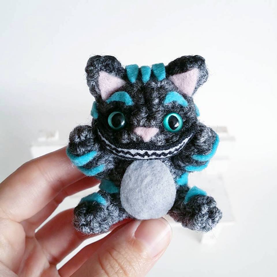 A blue and grey felt cat stuffed toy with a chesire smile designed by AnyaZoe@etsy using blue cat eyes from 6060eyes.